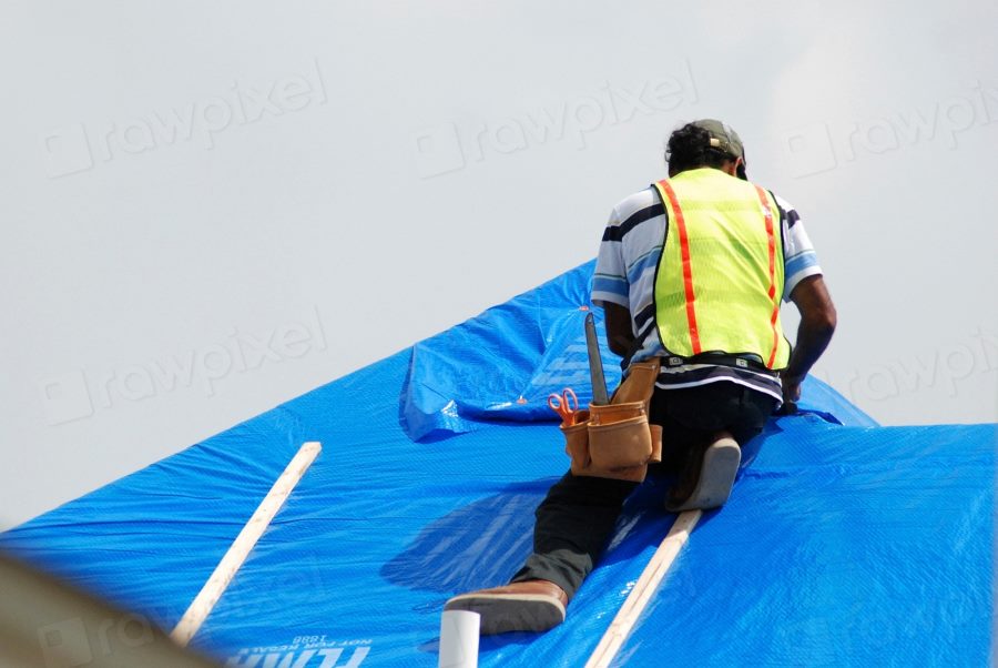 Roofing contractor carrying out repair work on a damaged roof surface